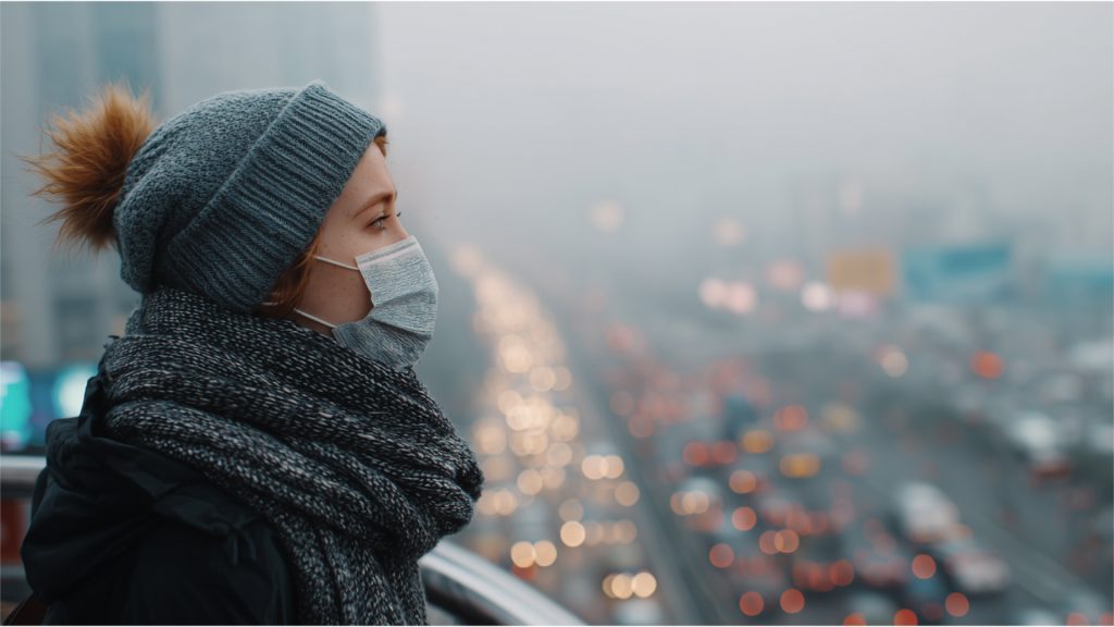 Young woman wearing mask outdoors in heavy smog, protecting skin from polluted air and PM2.5 particles.